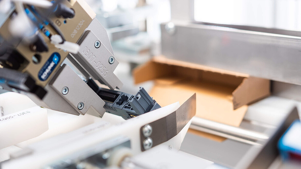 Widok z bliska automatu pakującego z kartonikiem